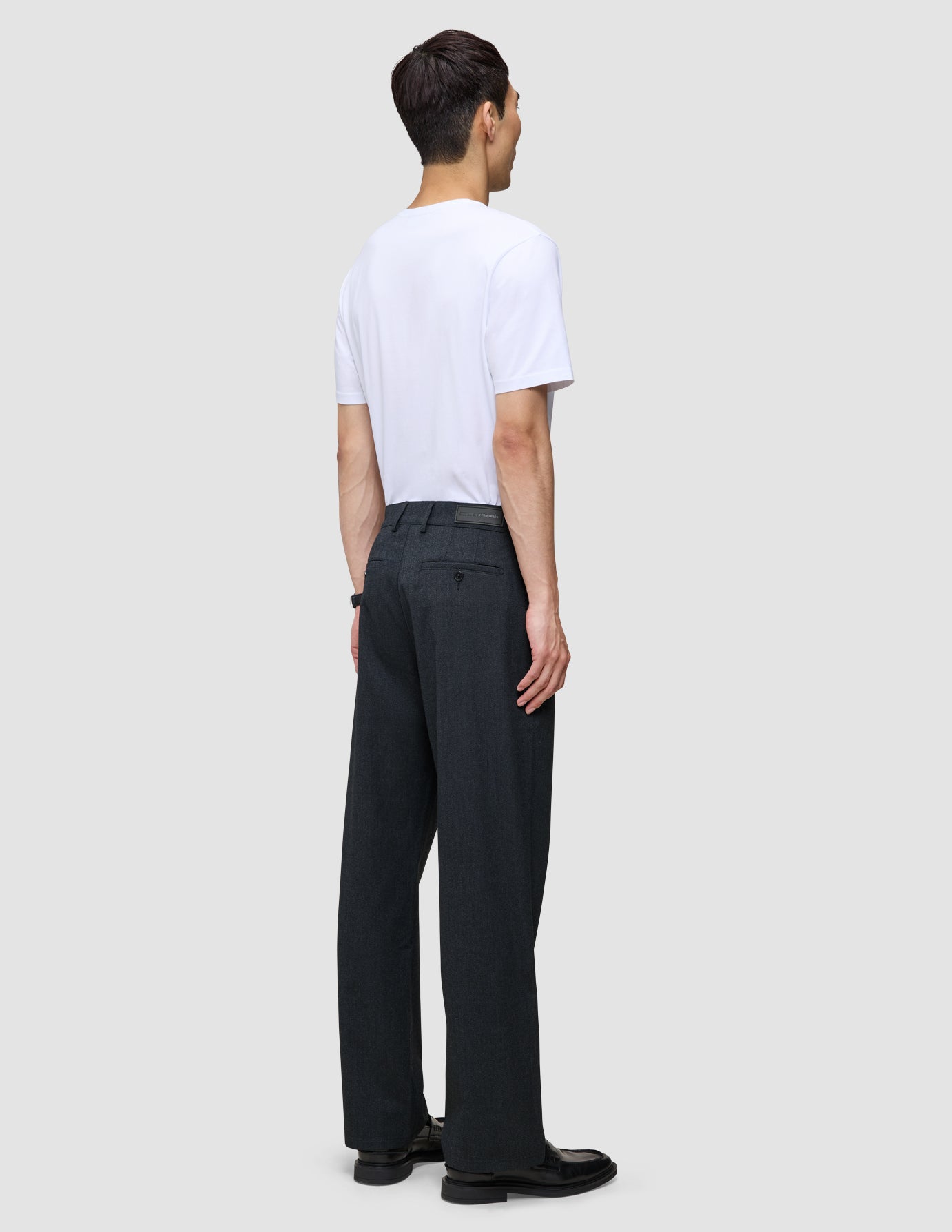 En person sett bakfra, kledd i en hvit T-skjorte og mørk marineblå Atelier Pants Relaxed.